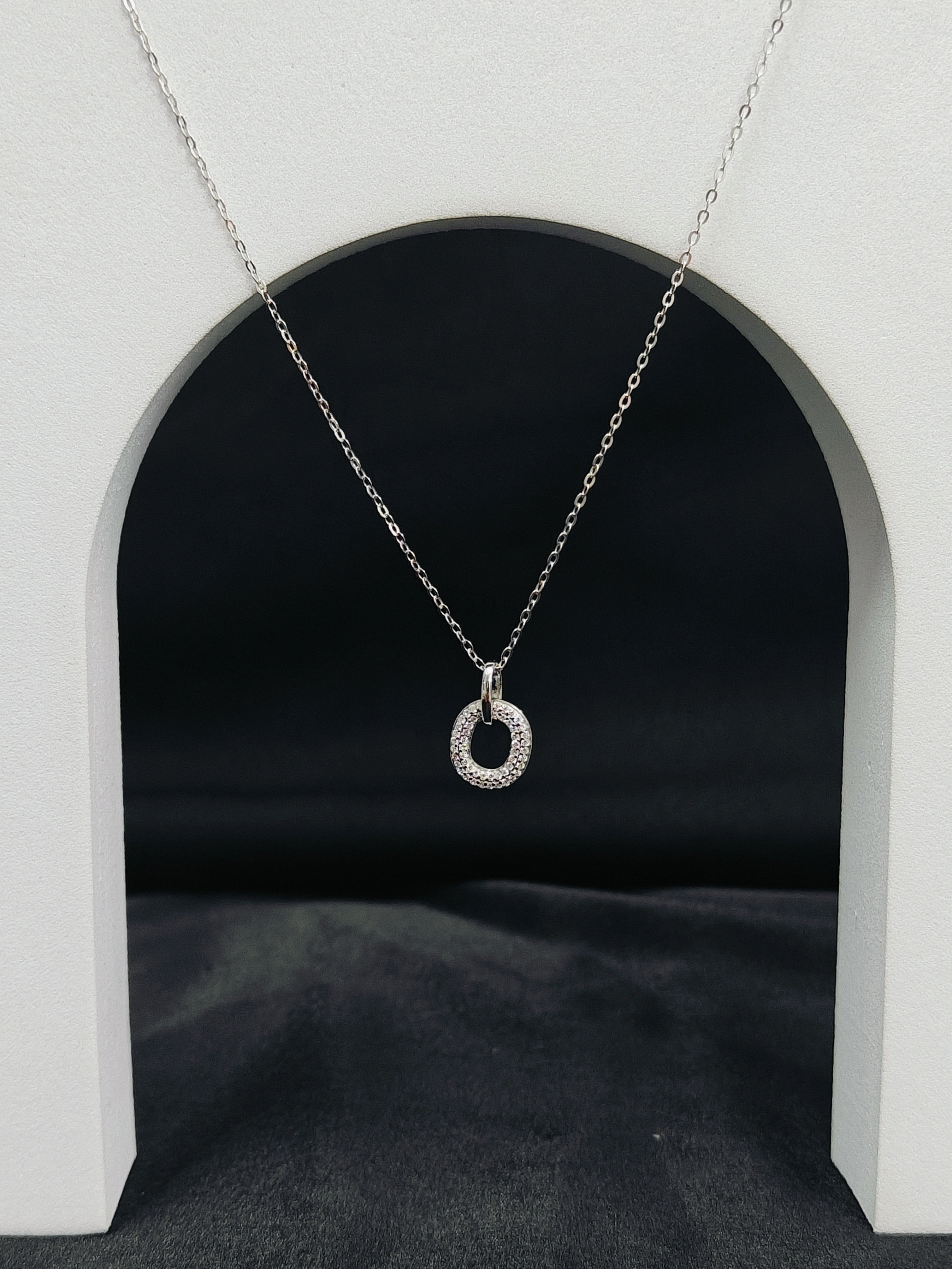 Silver necklace with a circular pendant on a dark background